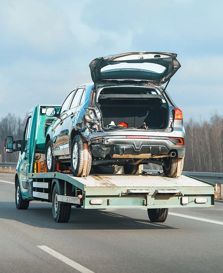 Damaged SUV being transported on a flatbed tow truck